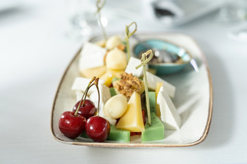A dish with four kinds of cheese, and walnuts. View from the end.