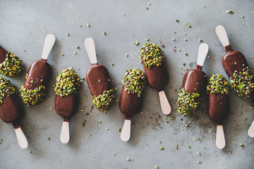 Ice cream popsicle pattern. Flat-lay of chocolate glazed ice cream pops with pistachio icing over...