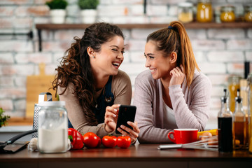 Sisters cooking together. Two friends having fun in kitchen. 