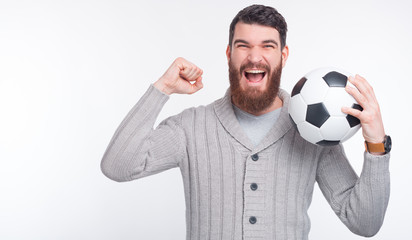 Goal! We have won! Young man is holding a soccer ball making winner gesture.