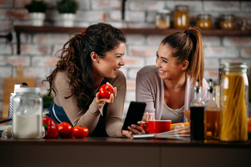 Sisters cooking together. Two friends having fun in kitchen. 