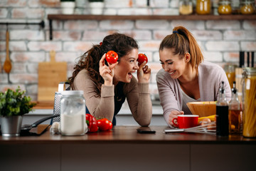 Sisters cooking together. Two friends having fun in kitchen. 