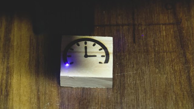 Burning clock icons with a laser on a tree. blue laser