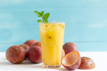 Passion fruit juice in a glass on a white wooden floor in a light blue background, summer drinks nonalcoholic