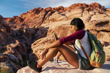 african american woman using smart phone on edge of cliff at red rock canyon