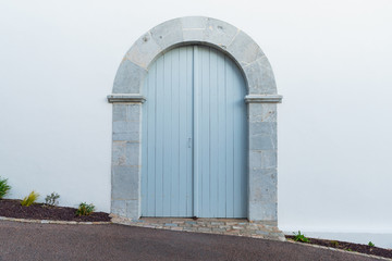 Light blue arched door with stone frame and white wall.