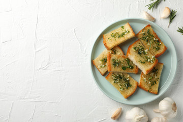 Plate with toasted garlic bread on white background, top view