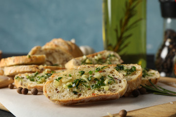 Baking paper with toasted garlic bread and oil on grey background, close up