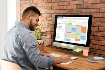Young man using calendar app on computer in office