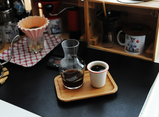 Manual brewing still life. Pouring filter coffee from carafe into cup. Bamboo tray. Third wave speialty aesthetics