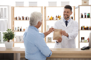 Fototapeta premium Pharmacist giving medicine to customer in drugstore