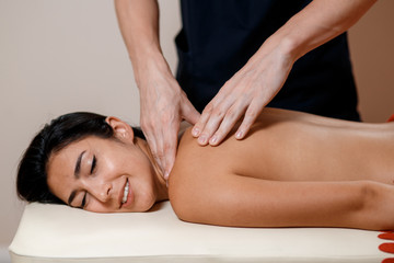 Fototapeta na wymiar A young woman gets a massage procedure. Masseur makes back massage.