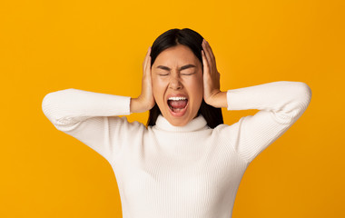 Asian girl covering her ears and shouting