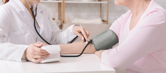 Doctor measuring blood pressure of senior patient at clinic