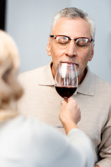 cropped view of woman giving glass of wine to friend