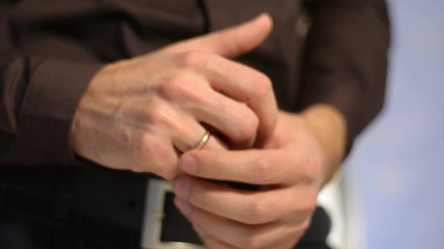 a man rotates a wedding ring on his finger. Young groom