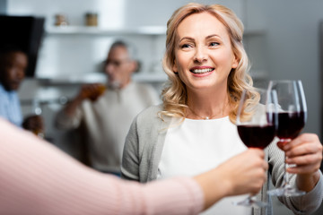 cropped view of woman clinking with smiling and attractive friend