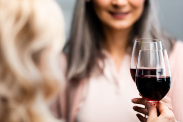 cropped view of smiling friends clinking with wine glasses