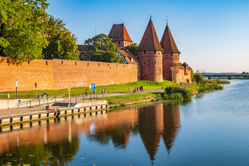 Naklejka premium Panoramic view of the western gate with defense towers of the Medieval Teutonic Order Castle in Malbork, Poland at the Nogat river bank