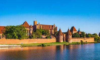 Naklejka na ściany i meble Panoramic view of the defense walls and towers of the Medieval Teutonic Order Castle in Malbork, Poland from across the Nogat river