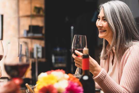 selective focus of smiling asian woman holding wine glass during dinner