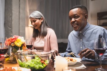 smiling multicultural friends talking and sitting at table during dinner