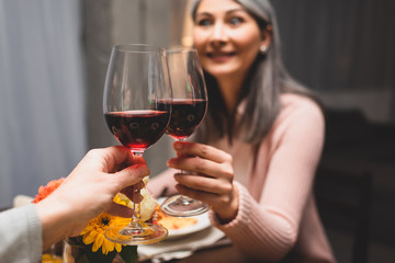 cropped view of woman clinking with her smiling asian friend during dinner