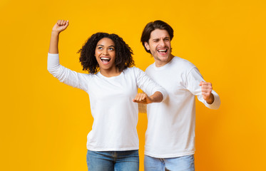 Joyful interracial couple having fun together, dancing and emotionally gesturing