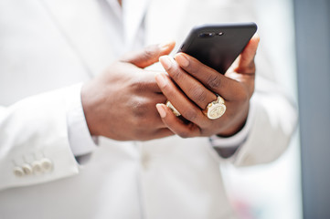 Close up hands of  handsome african american gentleman in formalwear looking at mobile phone.