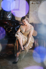 woman in a gold dress with a neckline in the image of 20-30 years old, with a diodema on her head,...