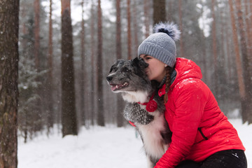 young woman kisses her dog in a winter park