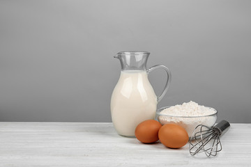 Raw eggs and other ingredients on white wooden table, space for text. Baking pie