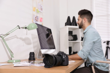 Professional photographer working at table in office, focus on camera