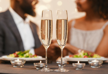 Two glasses of champagne over cuddling black couple