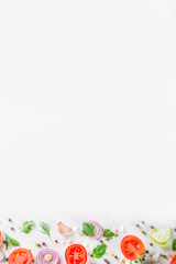 Fresh cherry tomatoes with basil, herbs and spices on white background, copy space for text top view. Ripe raw vegetables flatlay. Cooking food background, simple pattern