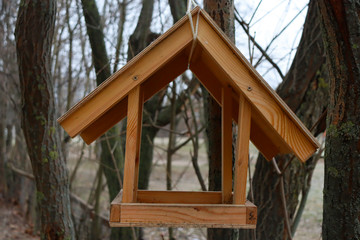 Wooden bird feeder on a tree. A house for birds made by man.
