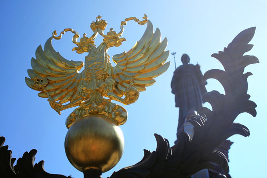 Iron coat of arms of the Russian Federation and the statue of Empress Catherine the great in the background