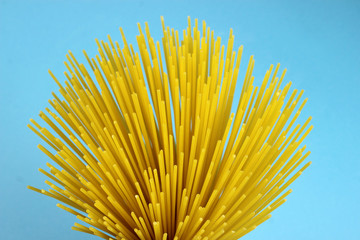 Yellow long spaghetti, top view on a blue background