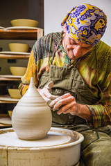 Potter working on potter's wheel with raw clay with hands, making new amphora bowl, small art business concept