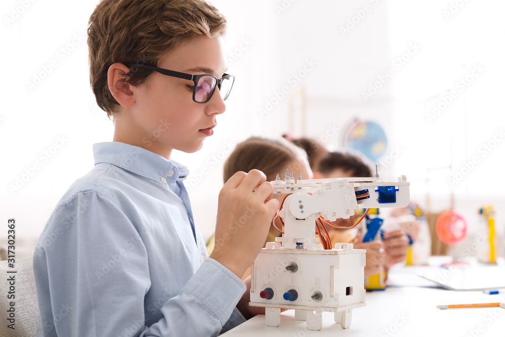 Fototapete Schoolboy building and programming robot in computer coding class