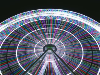 Obraz premium Ferris wheel at night long exposure light lines in a circle on a gradient sky background, copy space