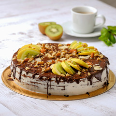 Tasty piece of chocolate cake with fruits, chocolate, apple, kiwi on cup of coffee americano, white background. Organic dessert sugarless. Healthy eating.