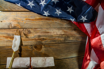 USA flag and ancient manuscript. Rolled-up constitution document on   national flag of America, wooden background. Declaration of the   Independence of the United States and national flag