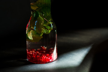Decanters with useful water with grenade and fresh mint in dark. Vitamins. Detox.