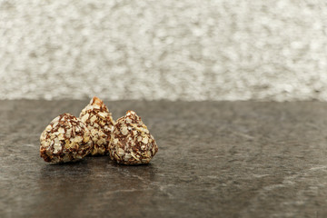 Whiskey with ice or brandy in a glass with truffles on a wooden table and a gray background. Whiskey with ice in a glass. Whiskey or cognac in a glass with truffles. Selective focus.