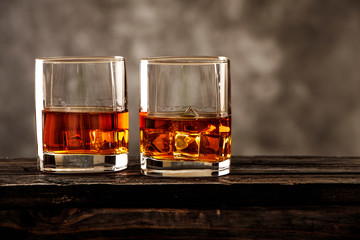 Whiskey with ice or brandy in a glass on a rustic background. Whiskey with ice in a glass. Whiskey...