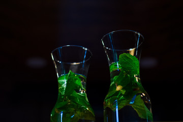 Decanters with useful water with grenade and fresh mint in dark. Vitamins. Detox.