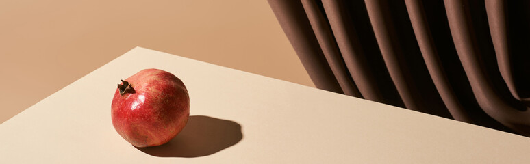 classic still life with pomegranate on table near curtain isolated on beige, panoramic shot