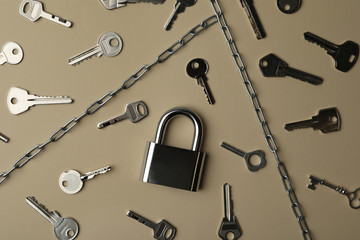 Obraz premium Steel padlock, keys and chains on beige background, flat lay. Safety concept