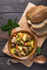 Irish dinner. Beef meat stewed with potatoes, carrots and soda bread on wooden background, top...